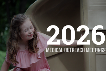 Girl with Down syndrome on a slide with text "2026 Medical Outreach Meetings"